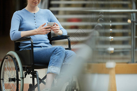 年轻的残疾妇女坐在轮椅上在手图片
