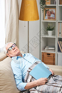 穿着眼镜的年长男子坐在沙发上在客厅图片