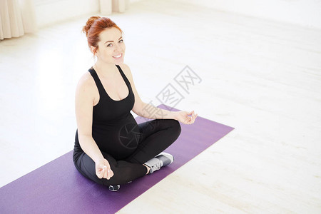 孕妇以交叉腿的瑜伽姿势站立时放松图片