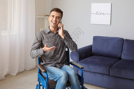 在家里用电话交谈轮椅的残疾青年男子图片