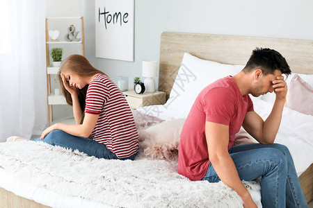吵架的夫妇坐在家里的床上背景图片