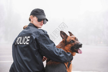 带着狗巡逻城市街道的女警官图片