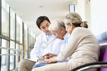 亚洲年轻医生在医院走廊使用数字平板电脑与老年夫妇患者讨论测图片