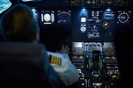 无法辨认的飞行员坐在控制面板上的后视图图片