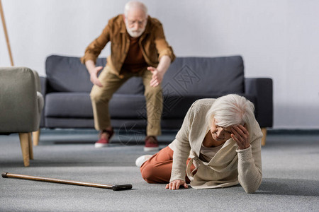 急忙帮助妻子躺在手杖旁边的地板上的妻子的老年男子有图片