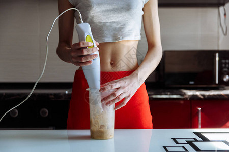 有手搅拌机的女人做甜香蕉蛋白奶昔图片