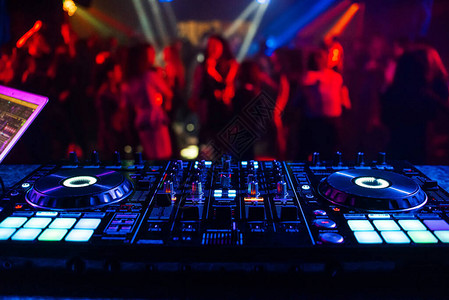 音乐控制器DJ混音器在派对上的一个夜总会里在舞者模糊的图片