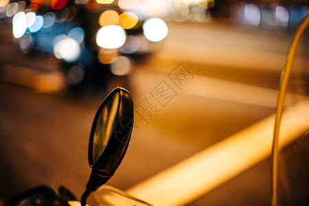 摩托车助力车后视镜的散焦模糊视图与背景中行驶的相邻汽车的图片