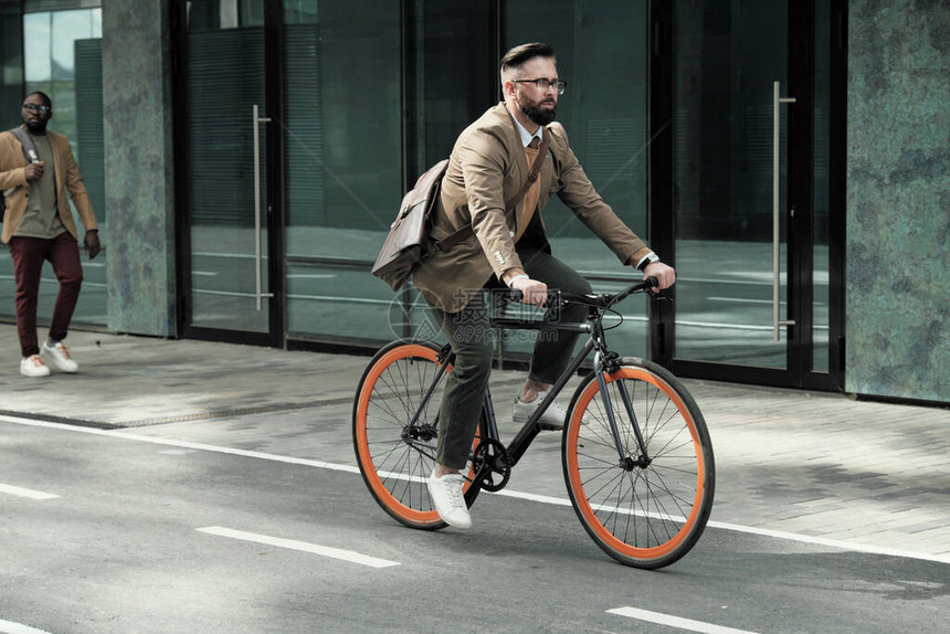 成熟的商人骑自行车在城市街道上骑着自行车上图片