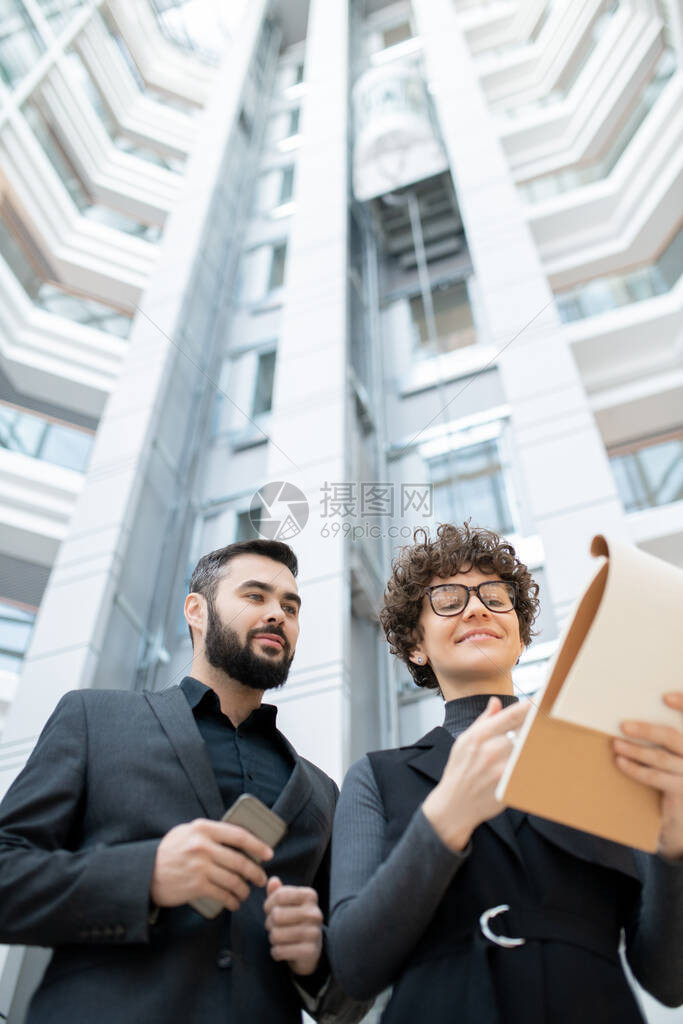 下面是戴着眼镜的微笑年轻女商人与办公室里留着胡子的同事分析销图片