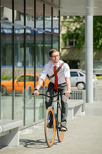 当代青年商人在阳光明媚的夏日骑自行车图片