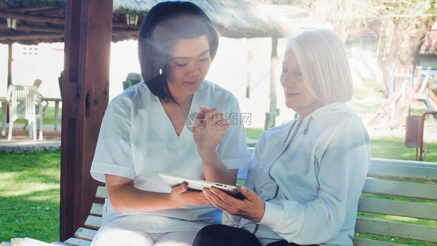 亚洲医生帮助老年退休妇女在花园里使用平板药幸福和退休概念图片