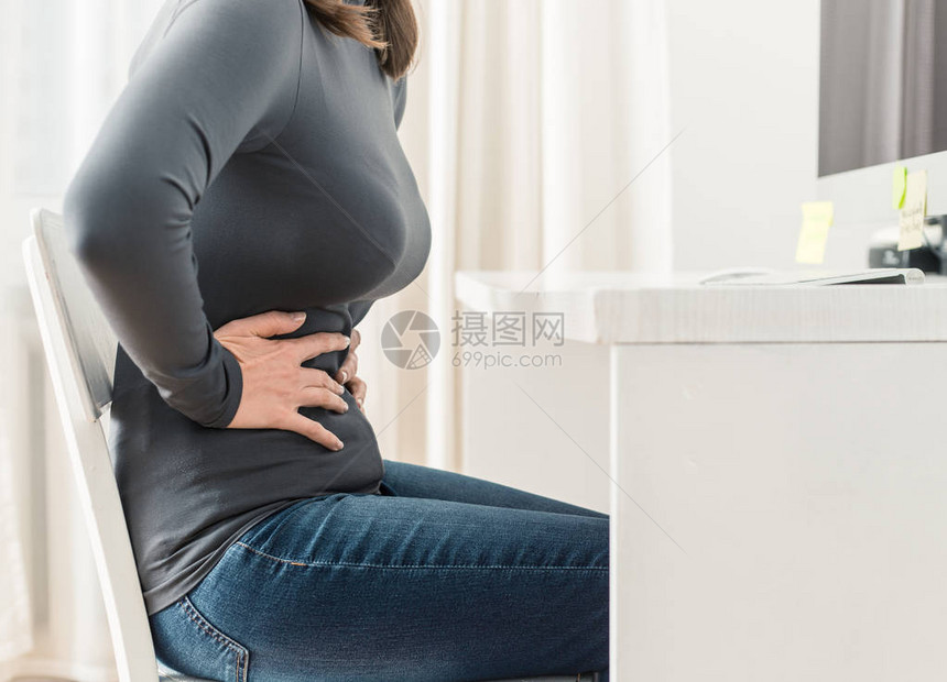 时间概念女人在书桌的尿液或胃痛图片