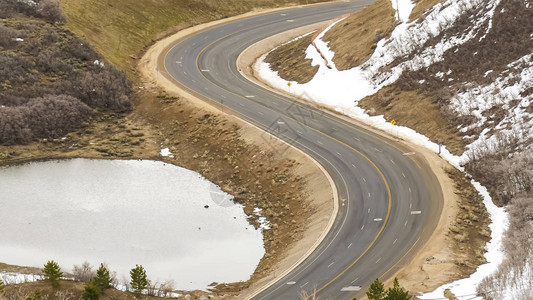 公路在冬季用雪坡弯曲穿过一座山峰图片