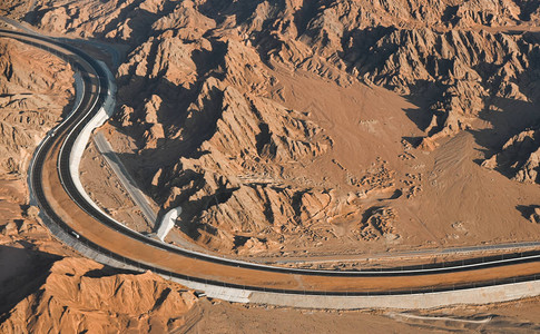 在沙漠的长高速公路上山地和沙滩之间图片