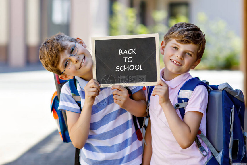 两个带背包或书包的小男孩上学路上的小学生健康的孩子兄弟和最好的朋友在街上户外在粉笔桌上回到学校快图片