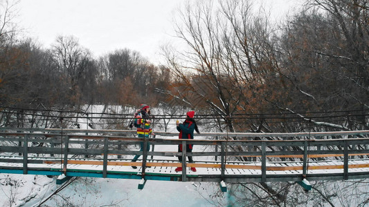 两个年轻多彩女站在寒冬森林的雪桥图片