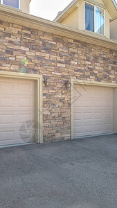 一个家的垂直的白色车库门靠着用石砖盖的外墙车库屋顶上方可以看到阁图片
