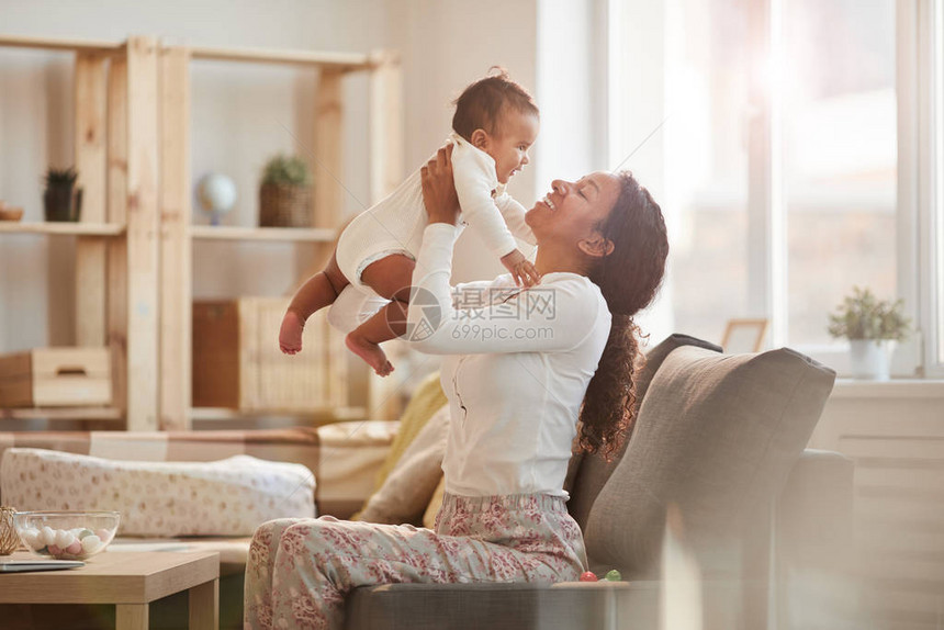 快乐的非裔美国母亲在家中玩耍时带着可爱小男孩的侧边肖图片
