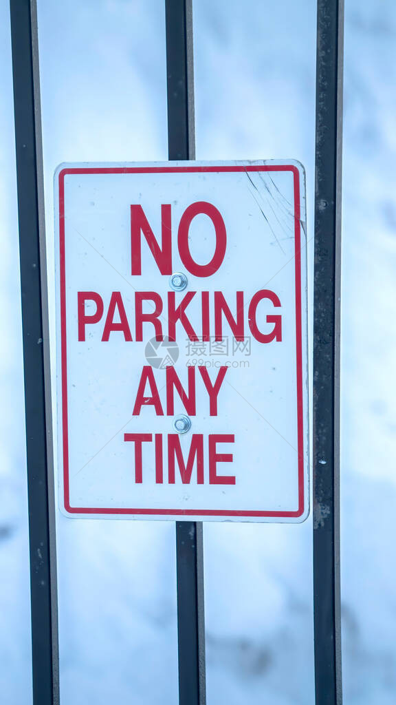 垂直禁止停车任何时间标志与新鲜的雪堆在模糊的背景标牌固定在金属图片