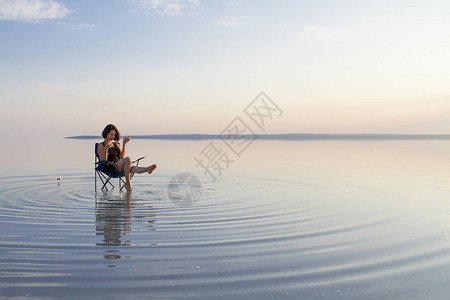 日落时妇女在海边坐图片