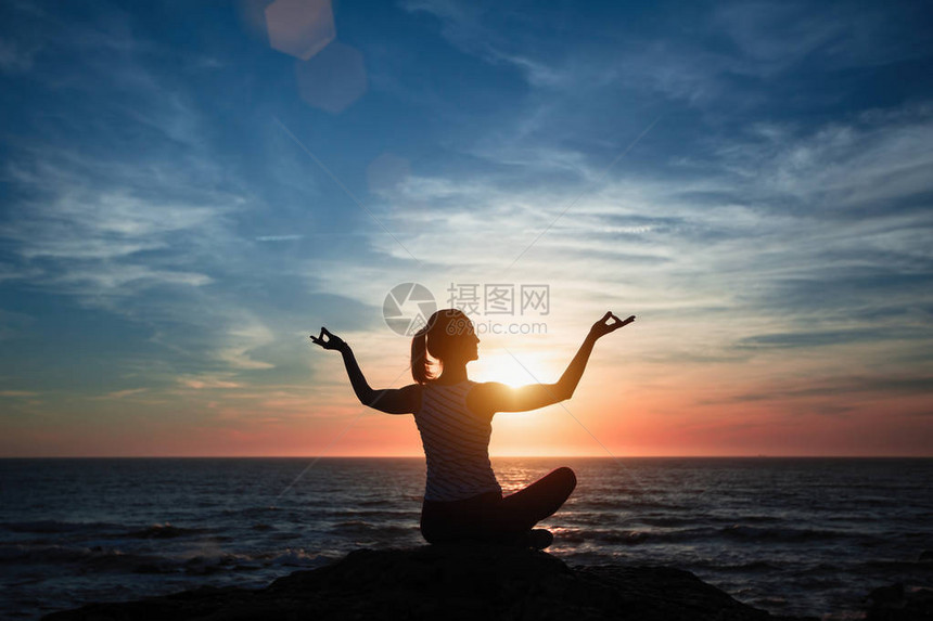 沉思的女孩瑜伽环绕在海边的沙滩上在图片