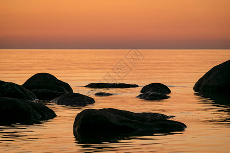 海边的橙色日落黑石月光在海面背景图片
