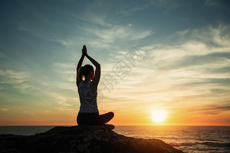 在惊人的日落时女瑜伽图片
