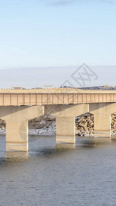 垂直架设有通向岩石和雪地形的长桥的光线平静湖图片