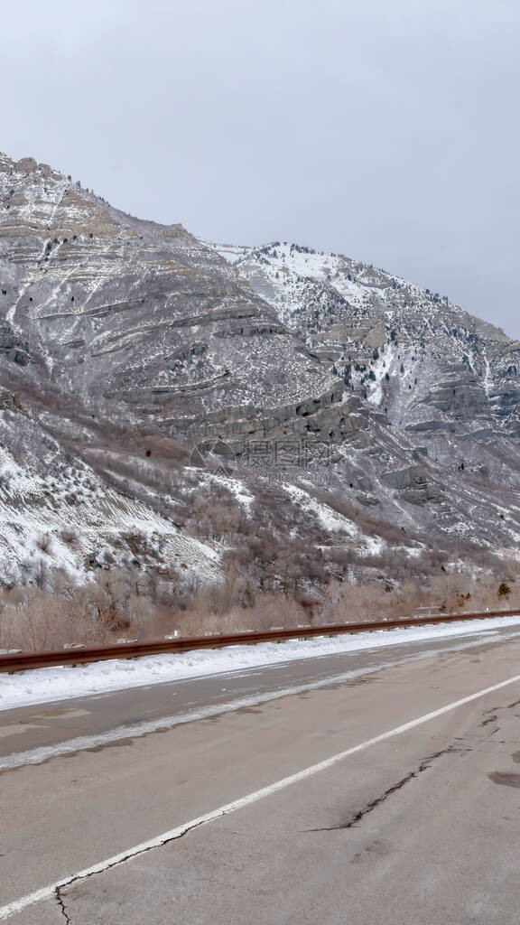 沿陡峭的雪山的垂直框架路在普罗沃峡谷有多云的天空背景高速公路与冬季犹他谷自然景图片