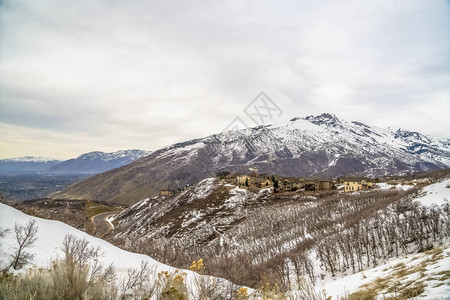 无叶树木的雪山在冬季有多层房屋和道路图片