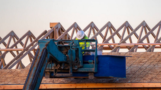 全景框架建造者或屋顶工在他工作时使用机械臂在新建房图片