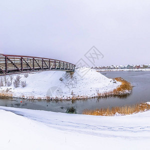 一座有雪覆盖海岸和金属桥的银湖广场全景图片