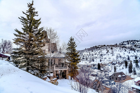 长青和位于公园城犹他州雪山上的房屋是冬季的景象图片