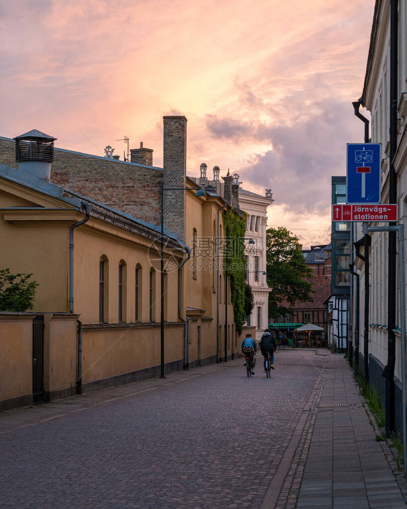 两人在日落时骑过瑞典古老城镇隆德的一条图片