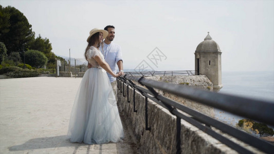 美丽的年轻夫妇度蜜月行动新婚夫妇在石头观景台上欣赏海景美丽的新婚夫妇图片