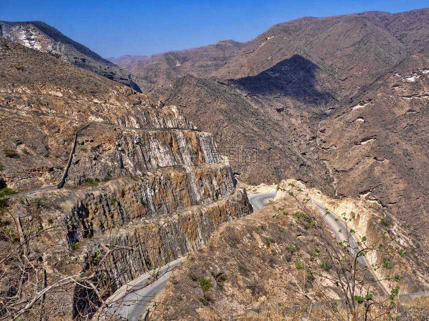 一条通向山坡的弯曲道路通往阿曼南部深峡谷图片