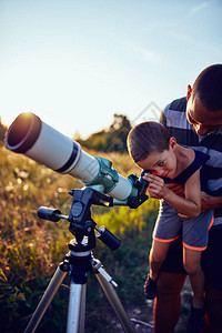 父亲和儿子用望远镜观察天空图片