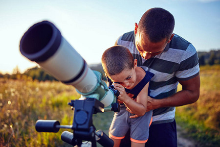父亲和儿子用望远镜观察天空图片