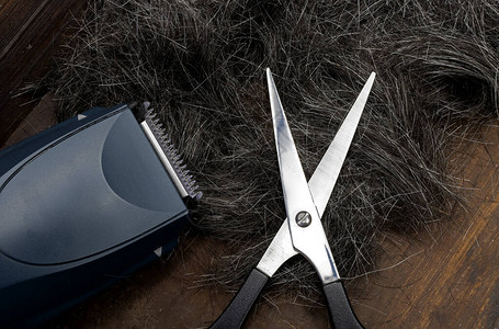 木制背景上的理发剪刀和剪掉的白发图片