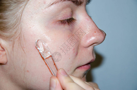 一位欧洲女孩正在将韩国涂在她的面膜上清洁毛孔油脂粉刺皱纹一个有皮肤问题的女孩的特写脸摩丝喷雾面部磨砂和洗面奶背景图片