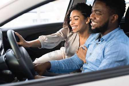 购买汽车喜悦的非洲裔美国人配偶在自动仓库内对新车辆进行图片