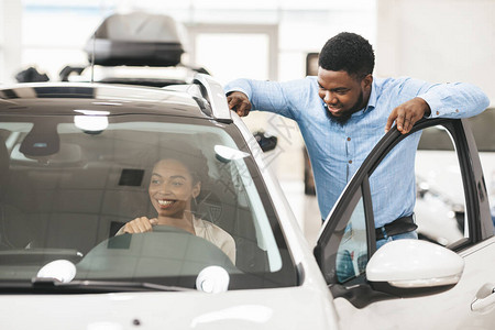 非洲裔美国人为他的妻子买车在经销店选择和测试汽车图片