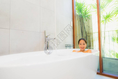 肖像年轻美丽的亚洲女在浴缸里洗澡图片