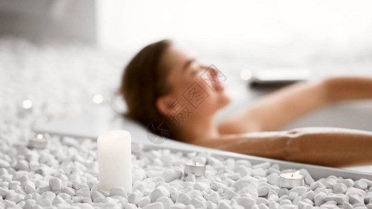 女青年在洗澡时放松用蜡烛洗浴气泡高清图片素材