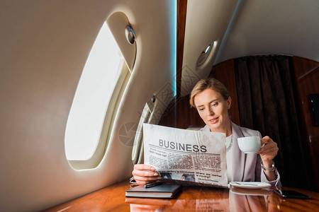 美丽的女商人在私人飞机上阅读商业报背景图片