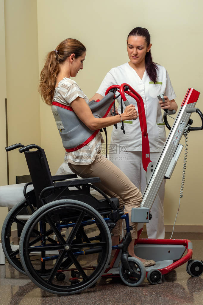 年轻女护士用液压电梯将残疾妇女移动到医院轮椅的完整肖像全长照片AC549图片