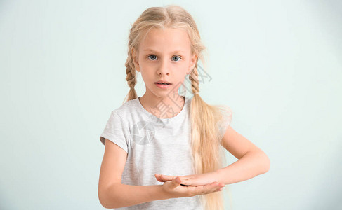 在浅色背景下使用手语的聋哑小女孩图片