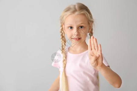 在浅色背景下使用手语的聋哑小女孩图片