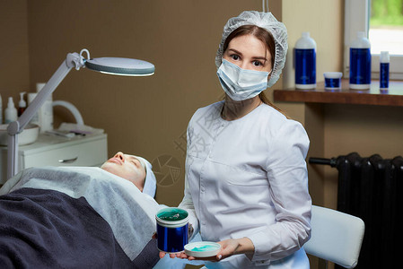 一位戴着医用面罩的女美容师在美容办公室的全电动美容床上图片